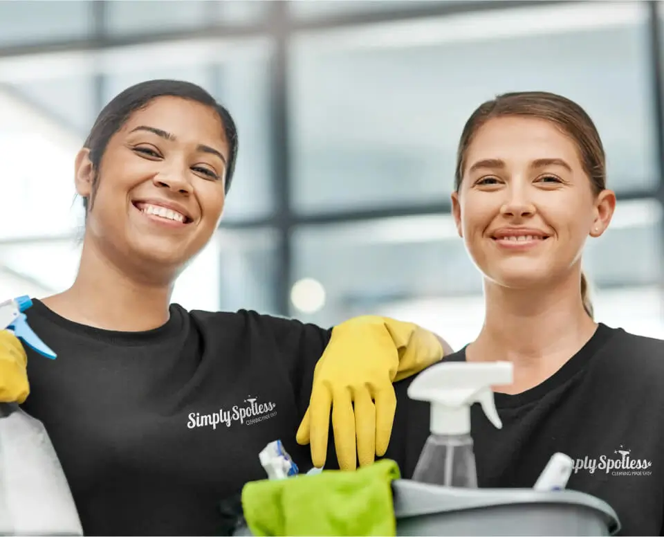 Two Simply Spotless Sydney workers smiling and holding cleaning equipment