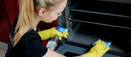 Simply Spotless employee cleaning an oven during a domestic cleaning service