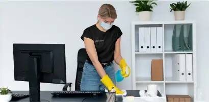 Simply Spotless office cleaning Simply Spotless employee cleaning a desk space during an office cleaning service