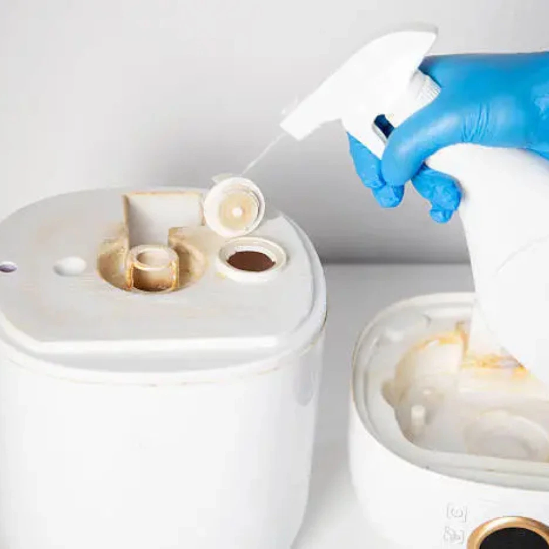 Dirty humidifier being sprayed with white vinegar to remove hard water stains 
